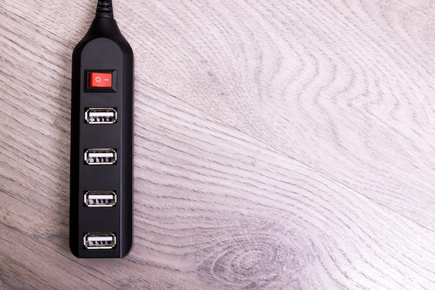 A close-up of a smart power strip, showcasing its multiple outlets and the on/off switch, with various electronic devices plugged in, such as phone chargers, lamps, and a television, highlighting its ability to cut off power to devices when not in use.