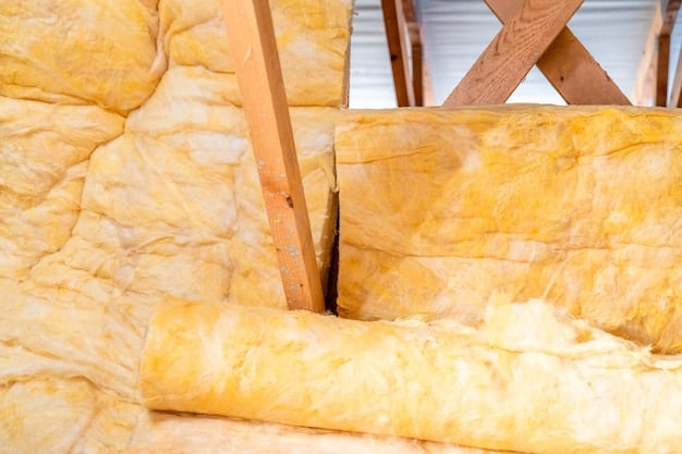 A close-up of attic insulation, showing thick layers of fiberglass batts covering the floor joists. A measuring tape indicates the depth of the insulation, ensuring it meets recommended standards. The image emphasizes the importance of adequate attic insulation for energy efficiency.