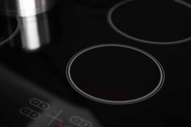 A close-up shot of an induction cooktop with pots and pans on the surface. The cooktop is sleek and modern, with digital controls and a minimalist design.