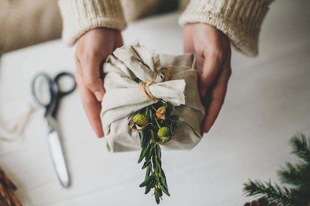 A close-up shot of hands wrapping a gift in reusable fabric wrap (Furoshiki) with a sprig of greenery tucked into the knot