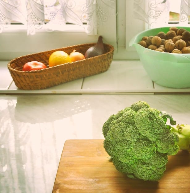 A brightly lit kitchen counter featuring assorted reusable beeswax wraps covering bowls of colorful fruits and vegetables