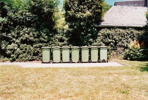 A well-maintained compost bin in a backyard garden setting, with visible layers of brown and green matter. The surrounding area is lush and green, highlighting the benefits of composting for plant growth.