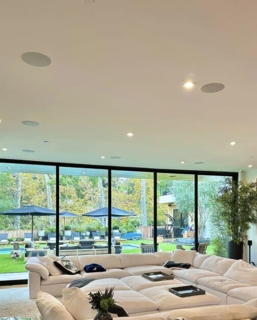 A well lit living room with large windows allowing natural light to flood the space, complemented by energy-efficient LED lighting fixtures.