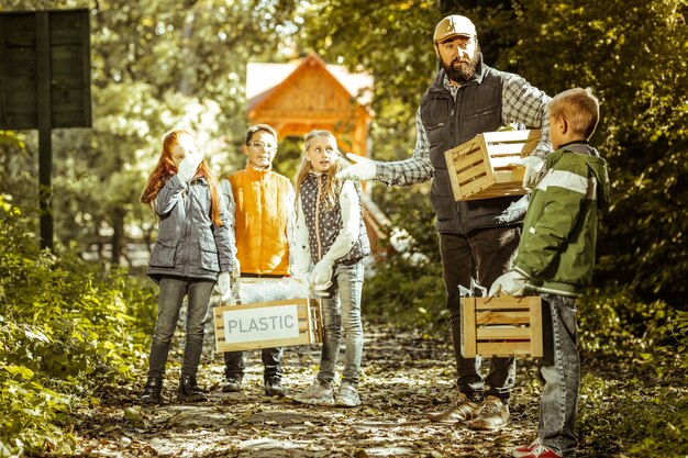 A friendly family is seen dropping off a box of old electronics at a local community e-waste collection event. The backdrop shows a clean and well-organized collection point with clear signage.