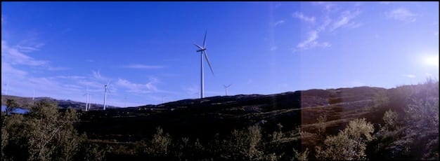 A split image showing a wind turbine farm on one side and a coal power plant on the other. The contrast highlights the shift from traditional fossil fuels to renewable energy sources, driven by policies like the Inflation Reduction Act.