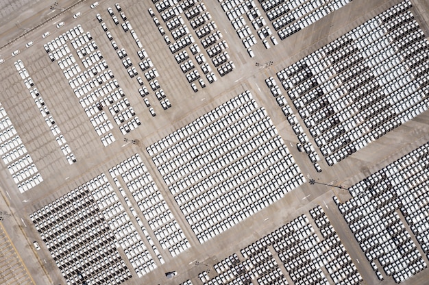 An aerial view of a large battery manufacturing plant in the United States. The scene includes delivery trucks, solar panels on the factory roof, and employees entering the building, emphasizing the growth of clean energy manufacturing jobs.